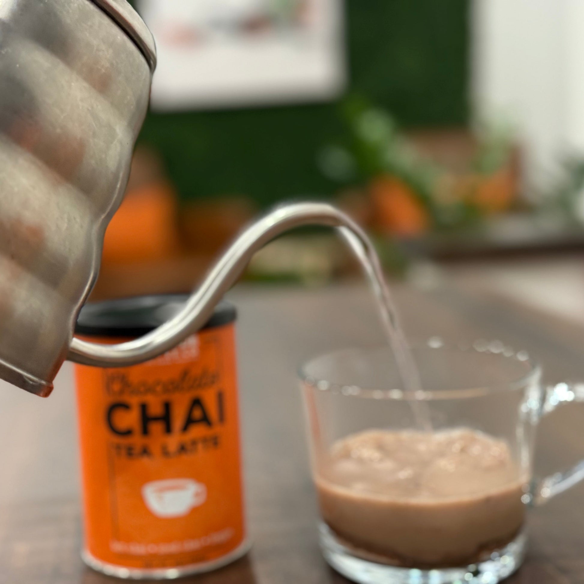 Chai tea latte being poured into a glass with a can of Chai Tea Latte in the background.