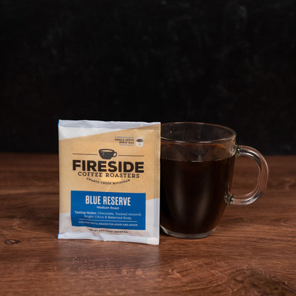 Fireside Coffee Roasters Blue Reserve coffee package with a glass mug of coffee on a wooden surface.