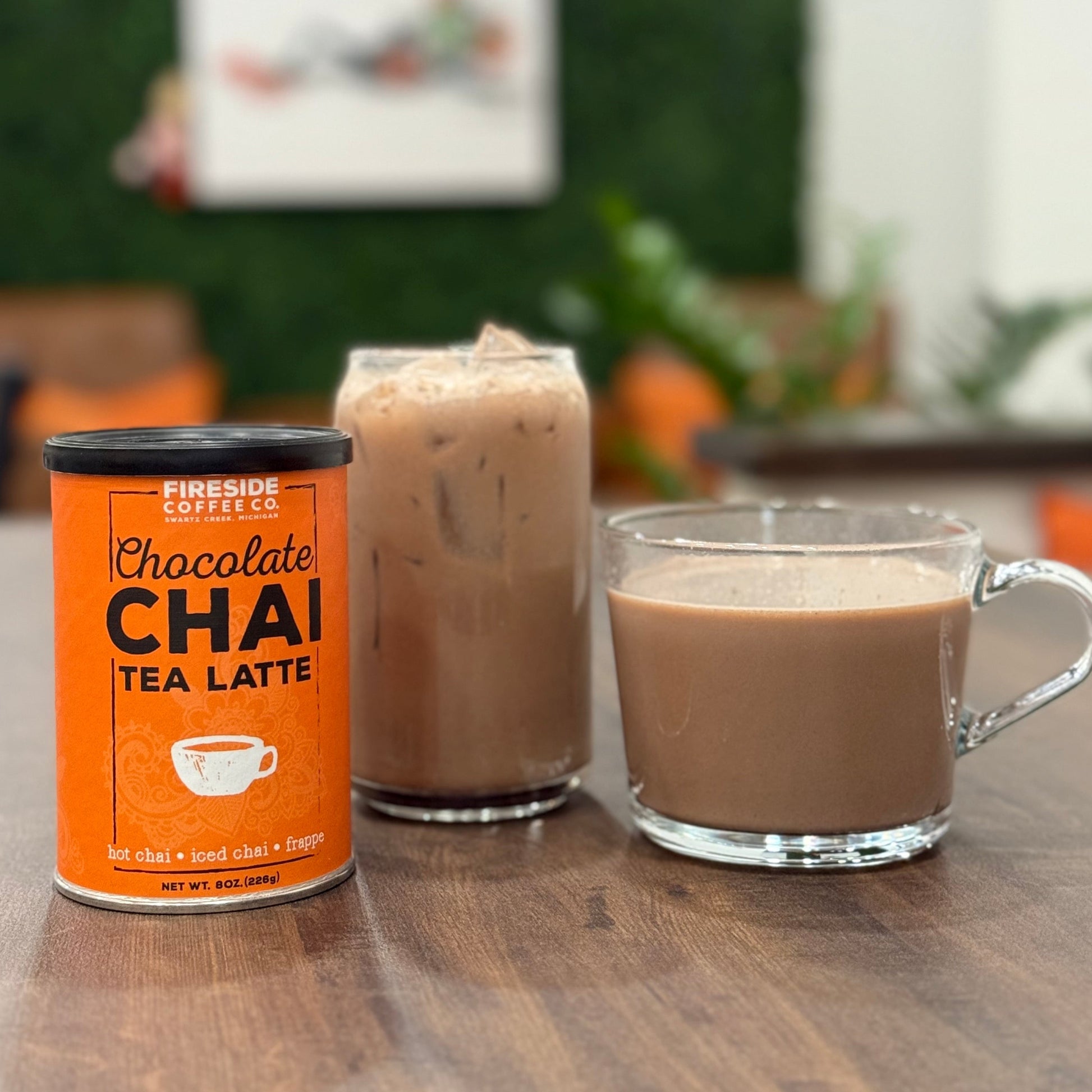 Can of Fireside Coffee Chocolate Chai Tea Latte next to a glass of the drink on a wooden surface.